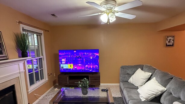 A living room with a television, sofa, and ceiling fan.