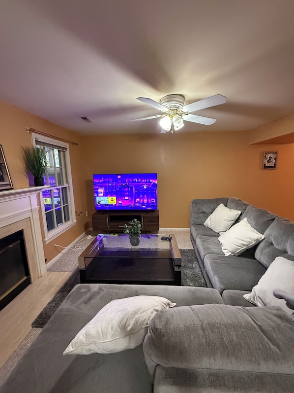 A living room with a television, sofa, and ceiling fan.