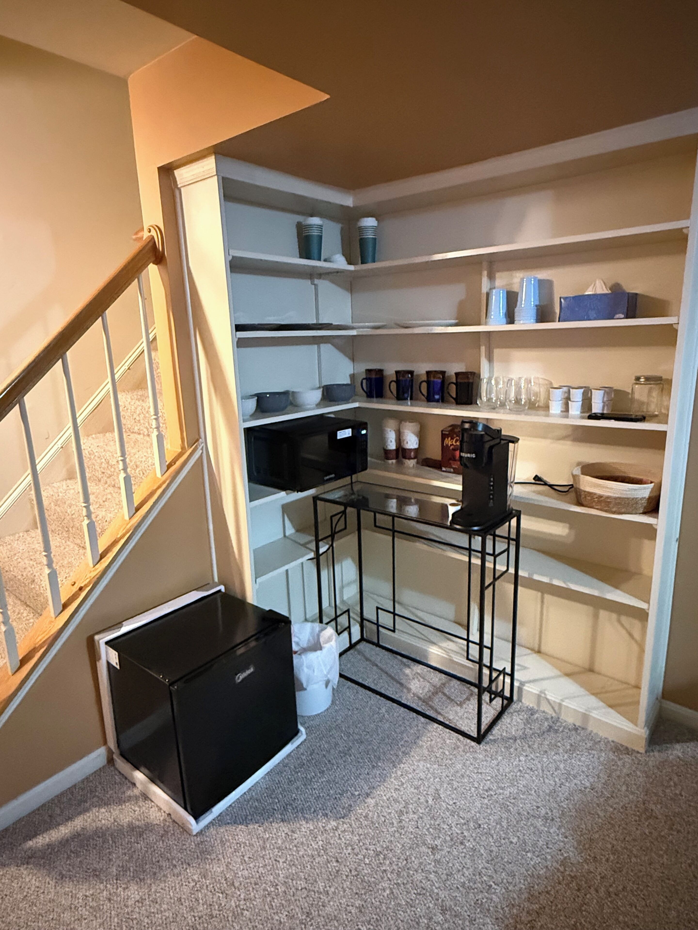 A compact kitchen with built-in shelves, a microwave, and a small table.