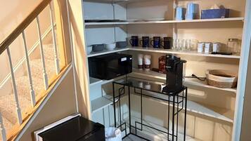 A compact kitchen with built-in shelves, a microwave, and a small table.
