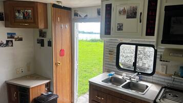 A compact kitchen with a sink, stove, and a window overlooking a grassy area.