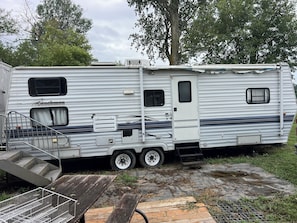 A white RV with a ramp, a small porch, and a window.