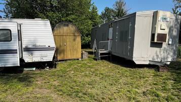 A row of RVs and a wooden shed in a grassy area.