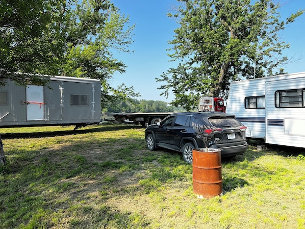 A campsite with RVs and a black SUV parked on grass.