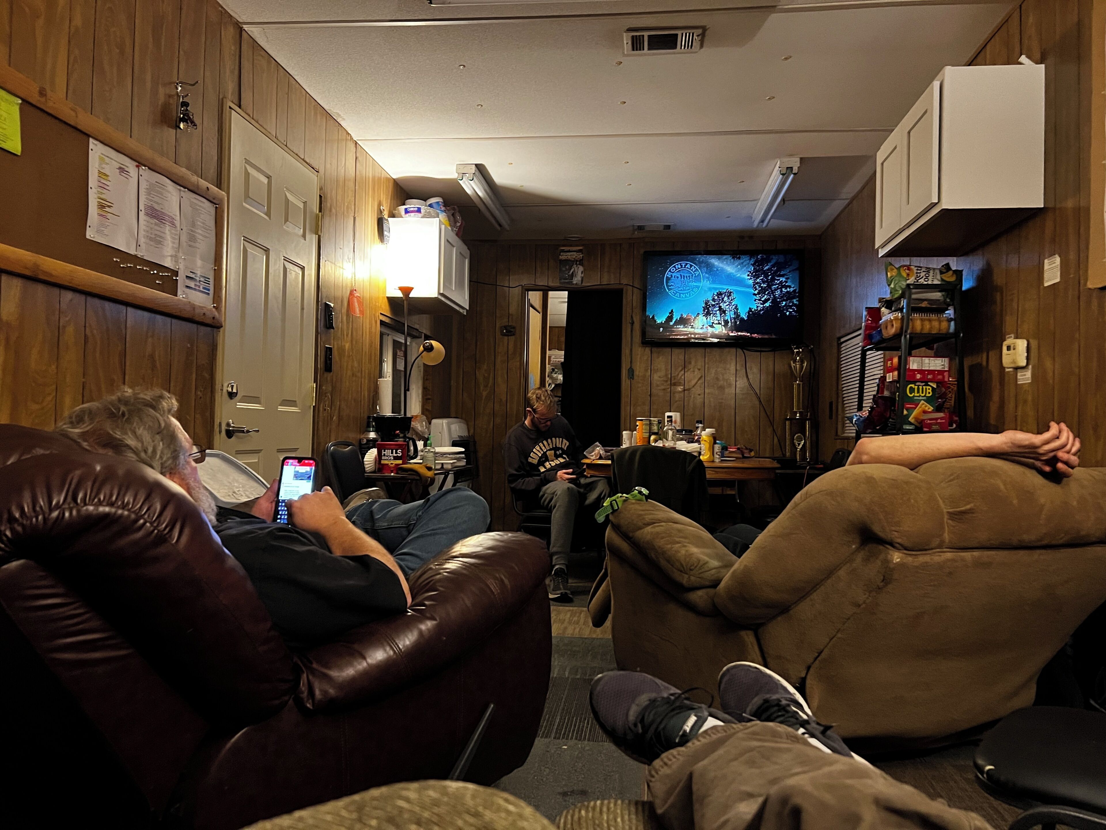 A room with leather recliners, a television, and a small table with various items.