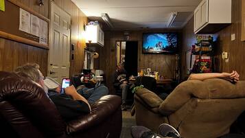 A room with leather recliners, a television, and a small table with various items.