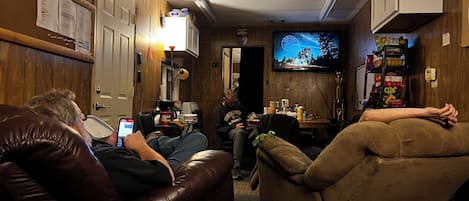 A room with leather recliners, a television, and a small table with various items.