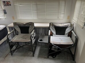 A room with two foldable chairs, a small table, and a window with blinds.
