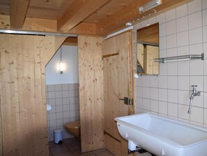 A wooden bathroom with a white sink, a mirror, and a toilet. - Alphütte Weissenberg Hütte, WC, 2 Schlafräume 5-Bettwohnung by Interhome (Lenk)