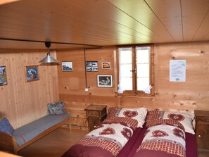 A cozy wooden room with a bed, a bench, and a small table. - Alphütte Weissenberg Hütte, WC, 2 Schlafräume 5-Bettwohnung by Interhome (Lenk)