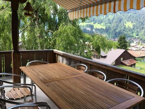 Ein Holztisch und -stühle auf einem Balkon mit Blick auf ein Dorf und einen Wald.