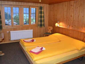 Ein Zimmer mit zwei Betten, einem fenster mit Vorhängen, einem Heizkörper und einer Holzwand.