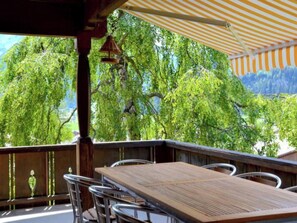 Eine Terrasse im Freien mit Tisch und Stühlen mit Blick auf einen bewaldeten Bereich.