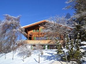 Eine Holzhütte mit Balkon, umgeben von schneebedeckten Bäumen.