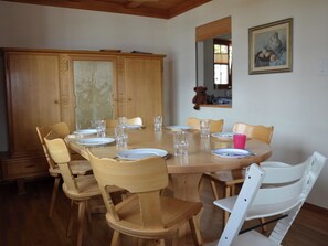 Ein Essbereich mit einem runden Holztisch, gedeckt für sechs Personen, umgeben von Holzstühlen.