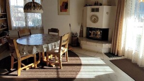 Un coin repas avec une table ronde et des chaises, une cheminée et une fenêtre avec des rideaux.
