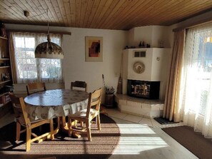 A dining area with a round table and chairs, a fireplace, and a window with curtains. - Steinbock # 2 Appartement/Fewo, Dusche oder Bad, WC, 1 Schlafraum 4-Bett-Wohnung by Interhome (Lenk)