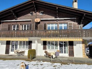A two-story wooden building with a balcony, large windows, and outdoor seating. - Steinbock # 2 Appartement/Fewo, Dusche oder Bad, WC, 1 Schlafraum 4-Bett-Wohnung by Interhome (Lenk)