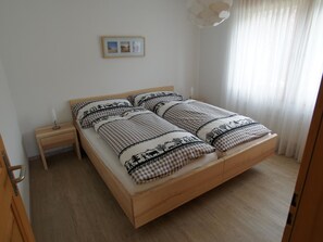 Ein Schlafzimmer mit einem Holzbett, einem Nachttisch, einer Nachttischlampe und einem Bild an der Wand.