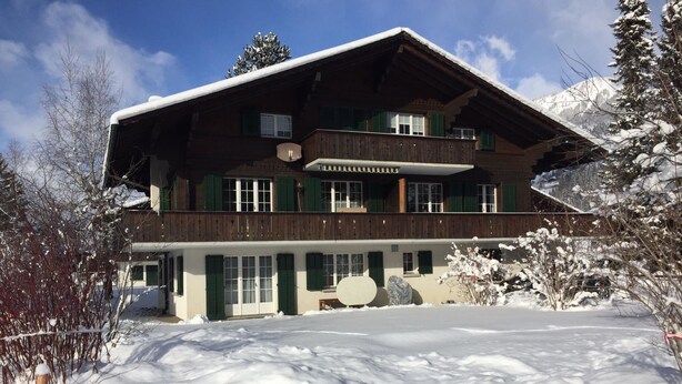 A two-story wooden chalet with a balcony, surrounded by snow-covered ground and trees. - Elena # 2 Appartement/Fewo, Dusche oder Bad, WC, 1 Schlafraum 2-Bett-Wohnung by Interhome (Lenk)