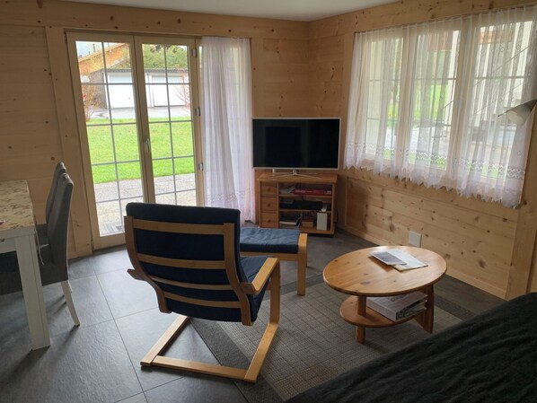 Une pièce comprenant une télévision, une chaise, une table et un canapé.
