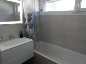 A bathroom with a white bathtub, a sink, and a shower. - Beryll # 2 Appartement/Fewo, Dusche oder Bad, WC, 3 Schlafräume 6-Bett-Wohnung by Interhome (Lenk)