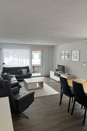 A modern living room with a sofa, coffee table, TV, and seating area. - Beryll # 2 Appartement/Fewo, Dusche oder Bad, WC, 3 Schlafräume 6-Bett-Wohnung by Interhome (Lenk)