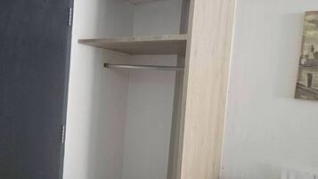 A room with a built-in wooden shelving unit, a door, and a pair of slippers on the floor.