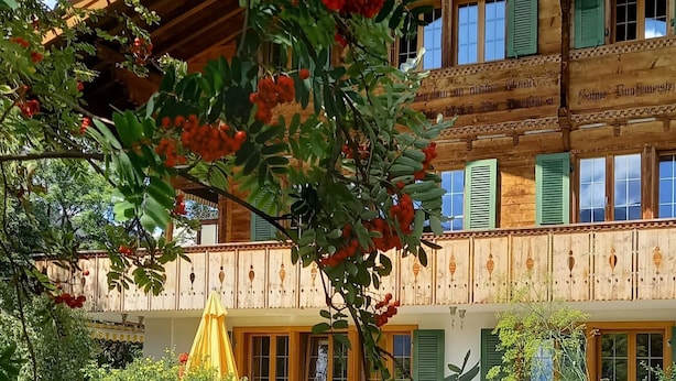 A wooden building with multiple windows and balconies, surrounded by greenery and trees. - Am Brüggli # 1 Appartement/Fewo, Dusche, WC, Erdgeschoß/Parterre 2-Bett-Wohnung by Interhome (Lenk)