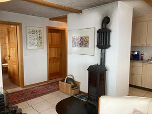 Een woonkamer met een open haard, houten deuren en een keukenhoek.