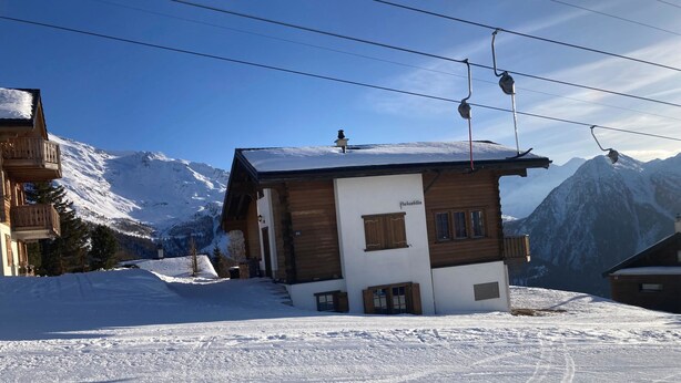 A wooden chalet with a ski lift in the background, surrounded by snow-covered mountains. - Chalet Pulsatilla Appartement/Fewo, Dusche, WC Pulsatilla by Interhome (Rosswald)