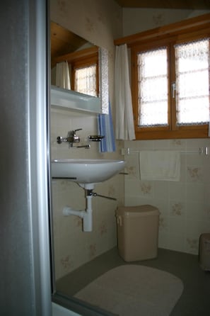 A bathroom with a sink, mirror, window with curtains, and a toilet. - Gletscherhorn # 2 Appartement/Fewo, Dusche oder Bad, WC, 1 Schlafraum by Interhome (Lenk)