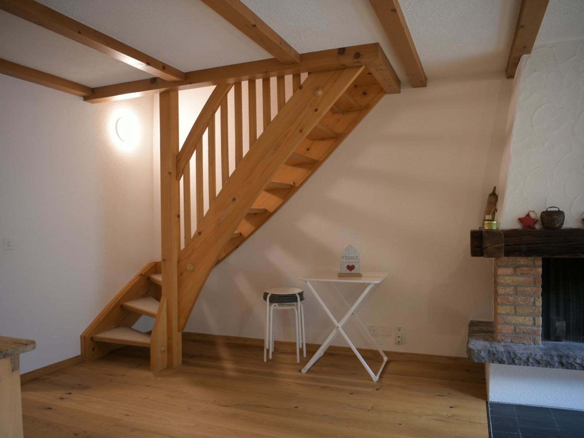 Eine Holztreppe führt zu einer Schlafempore mit einem kleinen Tisch und einem Stuhl.