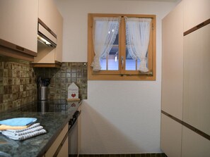 Una cocina estrecha con ventana, un salpicadero de azulejos y un pequeño letrero en la encimera.