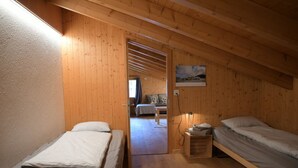 Ett rum med två sängar, träväggar, en tavla och ett fönster.
