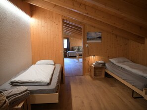 A room with two beds, wooden walls, a painting, and a window. - Chalet Sunnebort Appartement/Fewo, Bad, WC, 2 Schlafräume 5-Bettwohnung by Interhome (Lenk)