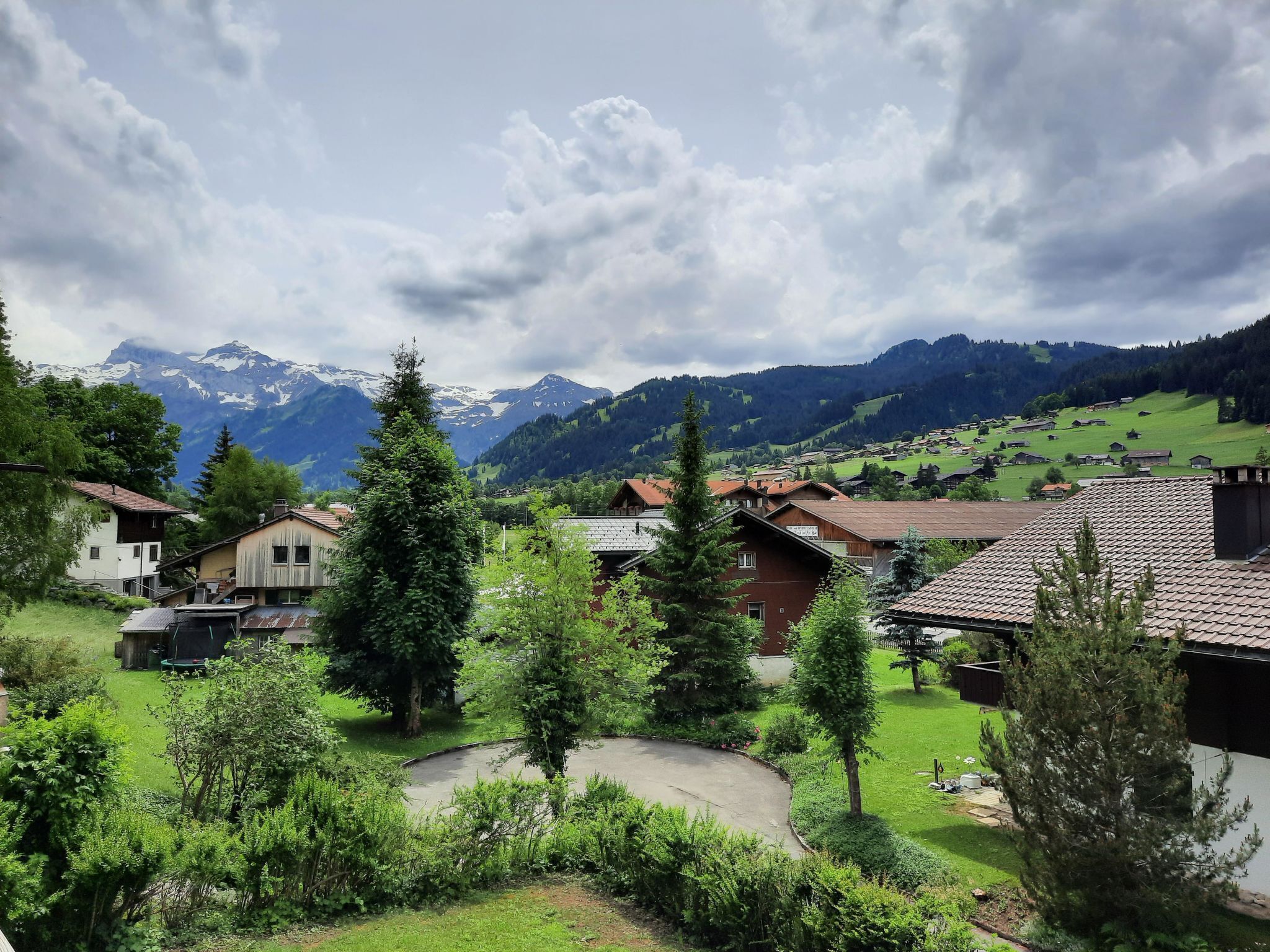 Ein ländliches Dorf mit traditionellen Häusern, einer kurvenreichen Straße und Bergen im Hintergrund.
