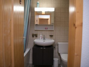 A compact bathroom with a white sink, dark cabinets, a mirror, and a toilet. - Chalet Sunnebort Appartement/Fewo, Bad, WC, 2 Schlafräume 5-Bettwohnung by Interhome (Lenk)