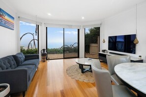 A modern living room with a sofa, a dining table, and a TV. - Ocean View Home with Pool - Balcony - Sleeps 10 (Marino)