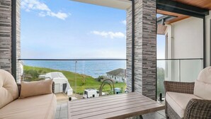 A balcony with a view of the sea, a wicker sofa, a wooden table, and a wicker armchair. - Ocean View Home with Pool - Balcony - Sleeps 10 (Marino)