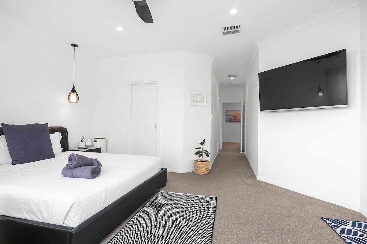 Une chambre à coucher avec un lit, une table de chevet, une lampe et un téléviseur fixé au mur.