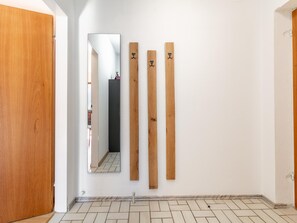 Un passadís amb una porta de fusta, un mirall i tres taules de fusta al mur.