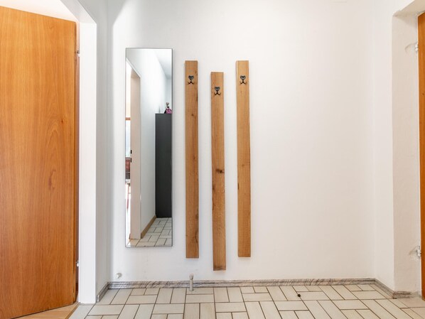 A hallway with a wooden door, a mirror, and three wooden planks on the wall.