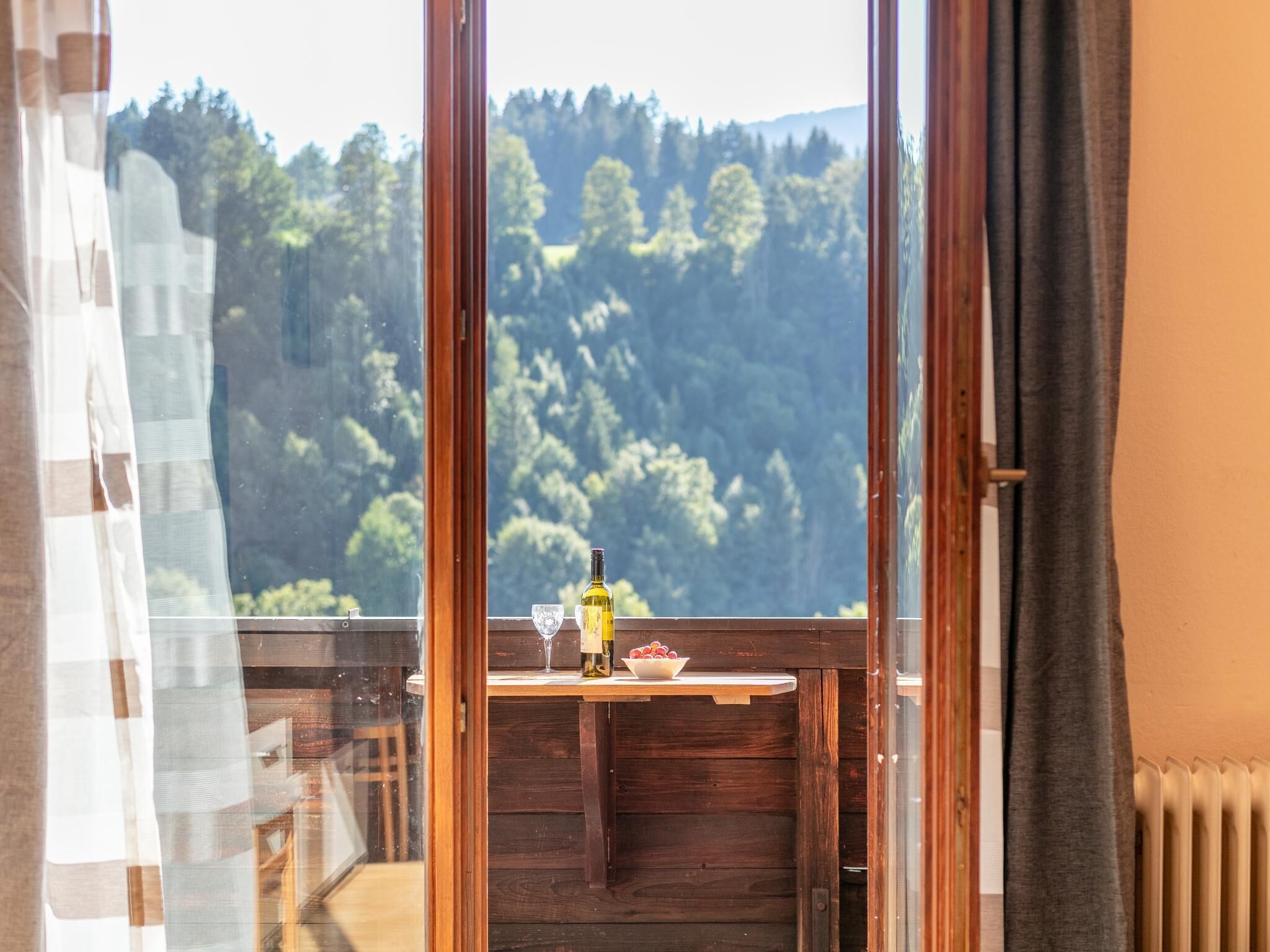 A room with a view of a forested area through a large window.