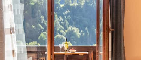 A room with a view of a forested area through a large window.