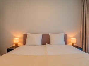 Ein Doppelbett mit zwei Kissen, einem Kopfteil und zwei Nachttischlampen.