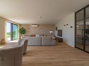 A spacious living room with a large sectional sofa, a coffee table, and a television. - Luxury villa by the Veerse Meer (Kamperland)