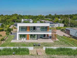 A modern two-story house with a flat roof, large windows, and a patio area. - Luxury villa by the Veerse Meer (Kamperland)