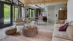 A modern living room with a large window, a dining area with natural light, and a cozy seating arrangement. - Vacation home near the North Sea beach. (Kamperland)