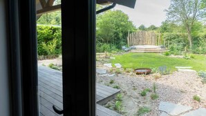 A view of a garden with a wooden deck, a grassy area, and a wooden fence. - Vacation home near the North Sea beach. (Kamperland)